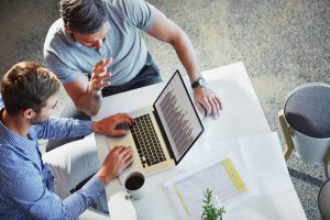 Shot of two colleagues using a laptop in a meeting at the office